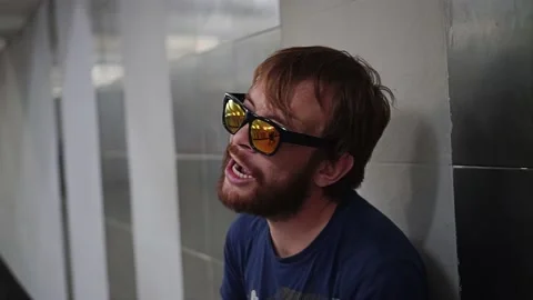 A guy with glasses sings while standing with his back to the wall Stock Footage 151047393