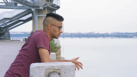 A Guy in the Glasses Troubled Looks Back in Waiting for a Meeting on the River Stock Footage 95411564