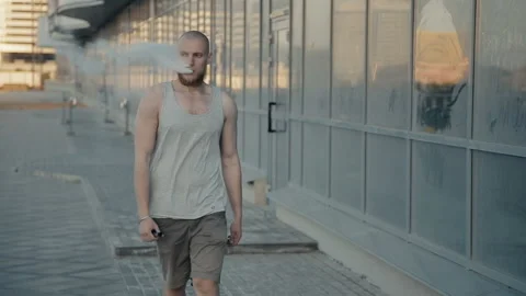 The guy goes and vaping in the evening on the street Stockbeeldmateriaal 85582713