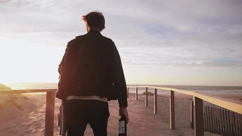 The guy goes to the beach, in his hand he carries a bottle of wine. Stock Footage 130515050