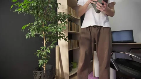 A guy goes to a bookshelf and chooses a book Stock Footage 264096432