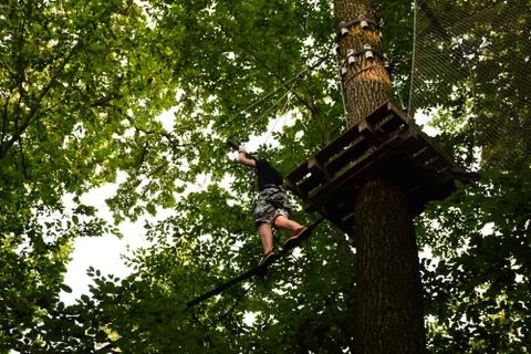 The guy goes through the obstacle course on the rope park Stock Photos