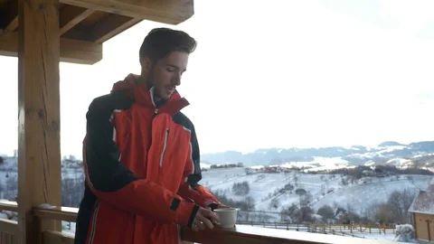 Guy grabbing a cup of hot beverage from a wooden railing on a deck in winte.. Stock Footage 72537612