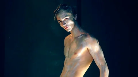 A guy with a gray makeup fixes hair and poses to the camera on black background Video stock 92706271