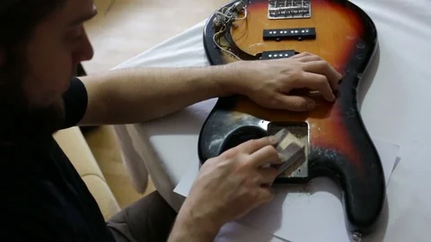 Guy grinds the deck of the guitar with sandpaper. The view from the top. Day, in Stock Footage 83562056