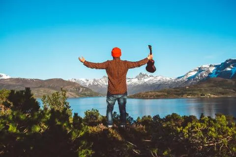 Guy with a guitar on the background of mountains, forests and lakes, wear a s Stock Photos