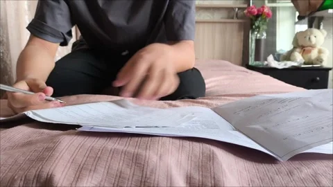 The guy hands are flipping through pages of documents while sitting on the bed Stock Footage 311653685