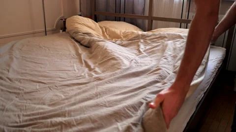 Guy hands shake blanket twice spreading over double bed 库存影片 101499376