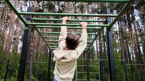 Guy hanging and goes through the horizontal bars on a sports ground. Stock Footage 312456698