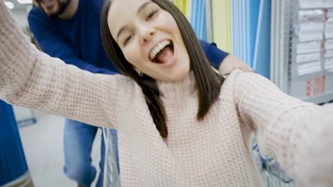 The guy has fun rolling the girl in the shopping basket in the supermarket, the Video stock 122978639