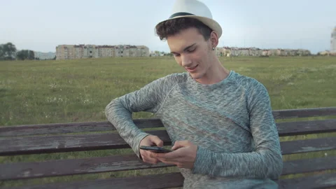 Guy in a hat and with an earring in his ear, who sits on a bench in the old city Stock Footage 166708500