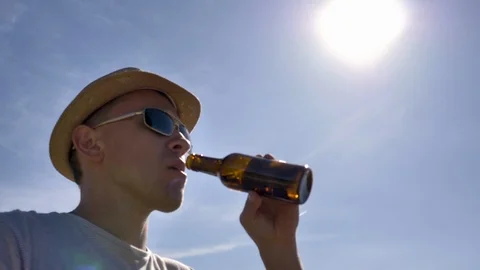 The guy in the hat is drinking beer on a bright sunny day. Stock Footage 120938007