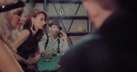Guy in the hat smokes a cigar and talks at the gambling table. Beautiful women Stock-Footage 105883584