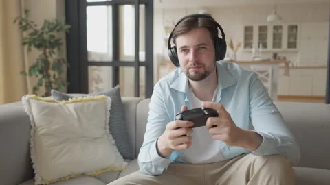 Guy in Headphones Playing Console Game on Sofa Frustrated After Losing the Match 動画素材 303086398