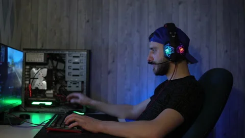 The guy in the headphones plays computer games and talks into the microphone Stock Footage 149215787