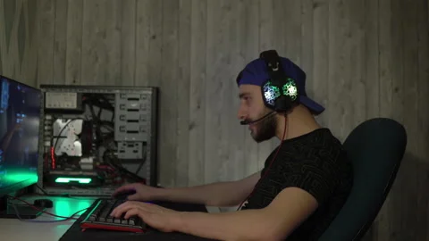 A guy in headphones plays computer games speaking into a microphone and bangs Stock-Footage 149216766