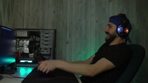 A guy with headphones plays computer games, speaks into a microphone and grabs Video stock 149217056