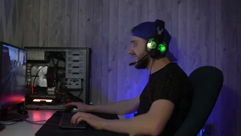 A guy in headphones plays computer games, speaks into a microphone and breaks Stock Footage 149217893