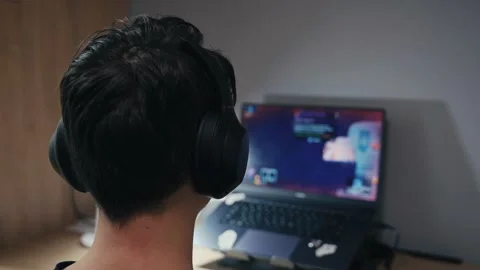 A guy with headphones at the table is playing a computer game. Stock-Footage 163328010