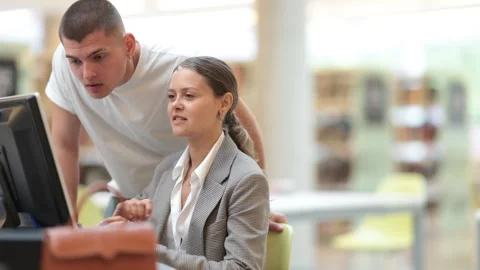 Guy helps a female student find information on the internet using a computer in Stock Footage 325835843