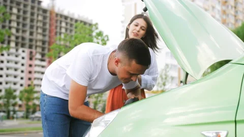 The guy helps the girl to replace the air filter in the car. The concept of Stock Footage 209523143