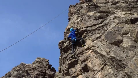 A guy high up on a cliff is trying to grab a ledge Stock Footage 166611811