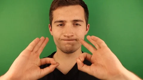 The guy from his hands makes glasses on his eyes on a green background, the Vídeo Stock 118854783