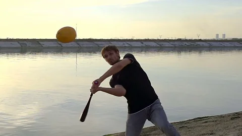 Guy hit a fruit bat slow motion. Man break vegetable piece. Baseball slowmotion. Stock Footage 72554609