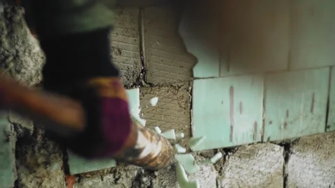 The guy hits the wall with a bat, chipping off the tile. close up Stock Footage 131219309