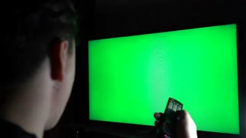 Guy hold remote control in hand and applying it to tv with green screen. Stock Footage 146461444