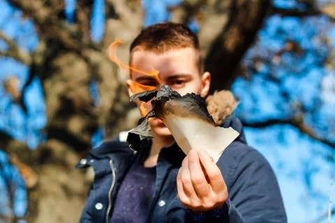 The guy is holding a burning leaf in his hand from a book Foto stock