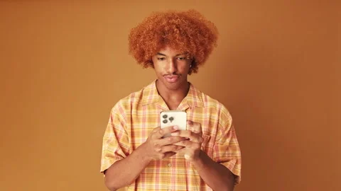 Guy holding phone, isolated on brown background in studio Stock Footage 253933241
