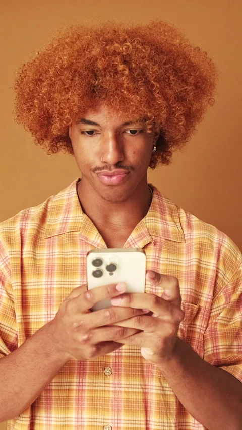 Guy holding phone, isolated on brown background in studio Stock Footage 254914247