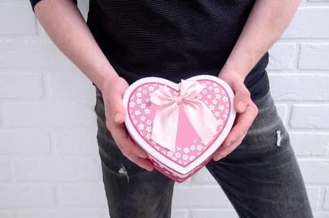 The guy is holding a pink box in the shape of a heart. Declaration of love. Foto stock