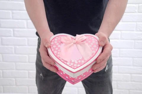 The guy is holding a pink box in the shape of a heart. Declaration of love. Stock Photos