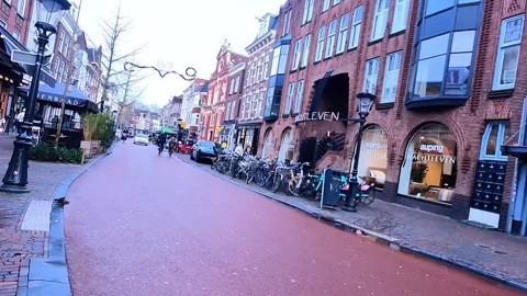 A guy holding a white bag walks along the street in Utrecht, Netherlands. There Stock Footage 328491854