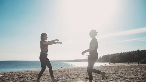 Guy holds in arms blond long-haired girl in red circles and kisses on beach Stock Footage 79396113