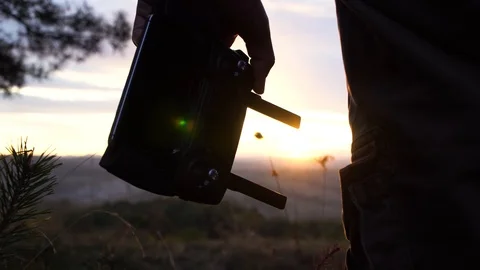 The guy holds the control panel from the quadcopter in his hands, sunset, glare Stock Footage 119713232