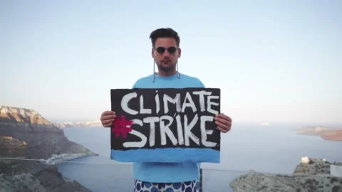 The guy holds a large poster in his hands with the words "Climate Strike" Stock Footage 159586763