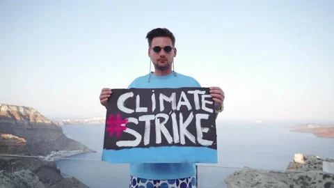The guy holds a large poster in his hands with the words "Climate Strike" Stock Footage 159586810