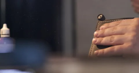 Guy Holds Leather Wallet in Hands. Sewn. Processes Edges with Polishing Machine Stock Footage 148360504