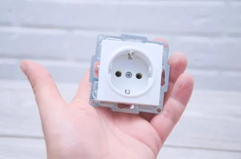 The guy holds a socket in his hand against a white loft. Stock Photos