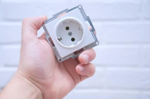 The guy holds a socket in his hand against a white loft. Stock Photos