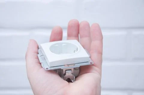 The guy holds a socket in his hand against a white loft. Stock Photos