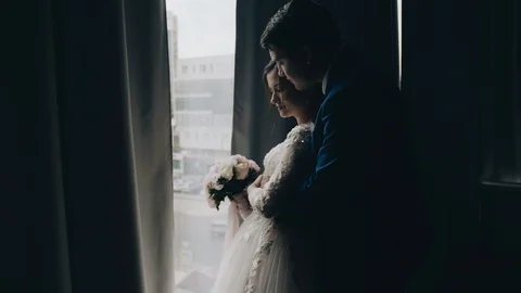 The guy hugs his girlfriend standing in front of the window with Stock Footage 118467697