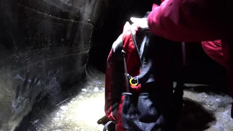 The guy in the ice cave opens a red backpack. Stock Footage 150304894