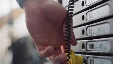 Guy Inserts Pin Into Cable Machine Weight Stack For Precise Resistance Video stock 307713806