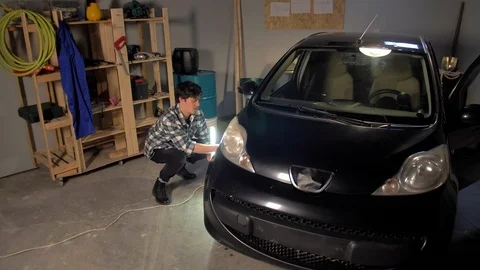 A guy inspects a car wheel in a garage Stock Footage 127436845