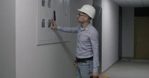 Guy inspects electrical panel to check wiring connections 스톡 동영상 309084448