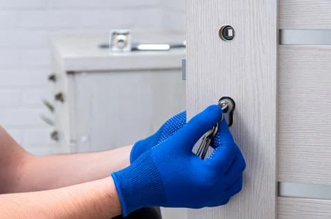 The guy is installing a new door lock in the room. Repair in the house. A guy Stock Photos